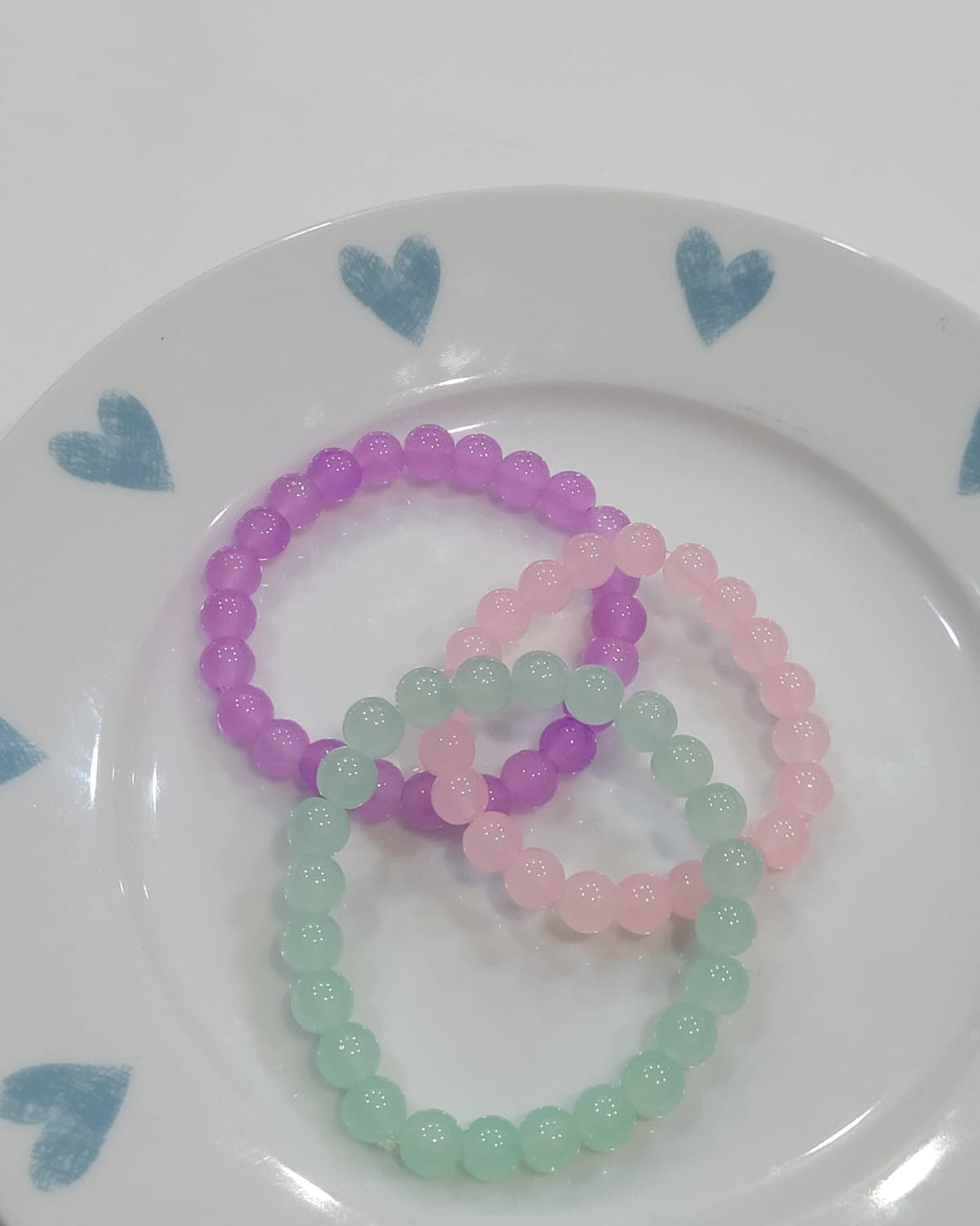 pastel beaded bracelets in mint green pink and purple on a white plate